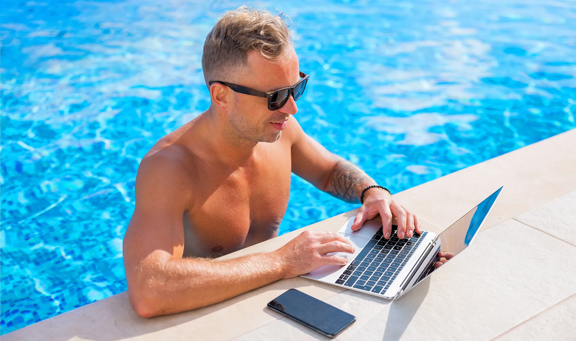 entrepreneur working remotely by the pool on vacation with laptop – balancing business and travel